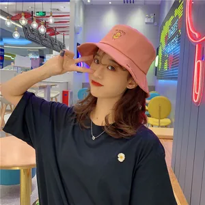Sweet pink bucket hat with potato embroidery worn by an Asian model in a stylish cafe environment