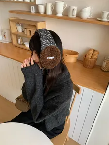 Vue latérale d'une femme portant des cache-oreilles en peluche marron dans un café