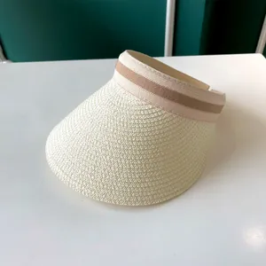 Gros plan d'un chapeau visière en paille blanc cassé avec ruban rayé élégant.