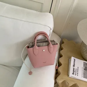 Détail du mini sac seau en cuir rose avec pochette intérieure à rayures et cordon