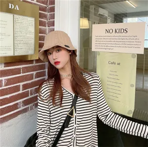 Detailed shot of a stylish beige pleated bucket hat for women in a cafe setting