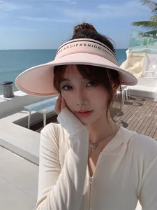 Gros plan d'un mannequin portant une visière rose à bord large sur la plage en été