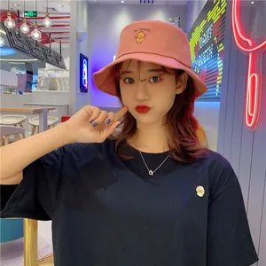 Pink bucket hat featuring cute Mr. Potato embroidery worn by an Asian model in cafe