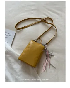 Primo piano di una borsa a tracolla gialla minimalista per cellulare con ciondolo