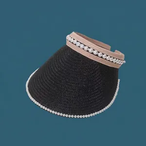 Detailed view of elegant black straw sun visor decorated with white pearls on the brim and band