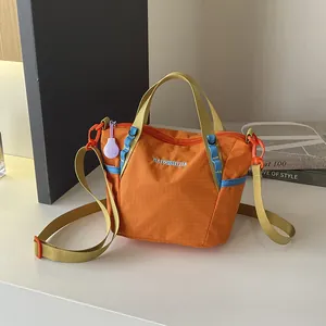 Detailed view of bright orange grid texture nylon crossbody bag with yellow straps