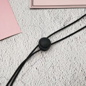 Vista dettagliata di un cordino antivento nero regolabile con fermo in plastica rotondo per cappelli
