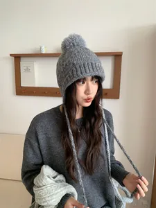 Mujer con gorro de punto gris con pompón y lazos de protección para las orejas
