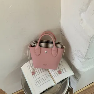Vue détaillée d'un mini sac seau rose posé sur un livre ouvert pour une ambiance lifestyle