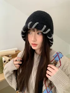 Detailaufnahme einer schwarzen Strickmütze mit grauen Kontrastnähten am Modell