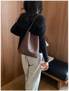 Vista detallada del bolso tipo cubo tejido marrón para mujer en un entorno de vida minimalista