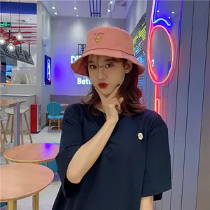 Close-up of a pink bucket hat featuring a cute potato embroidery worn by a model