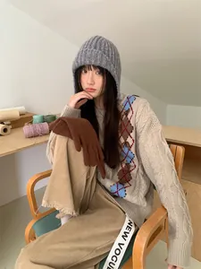 Asiatisches Model trägt eine graue, grob gestrickte Pilotenmütze mit Ohrenklappen