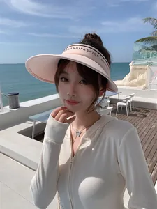 Gros plan d'une visière pare-soleil rose portée par un mannequin sur une plage ensoleillée