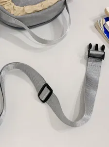 Detail van de afneembare schouderband van een grijze lichtgewicht crossbody telefoontas.