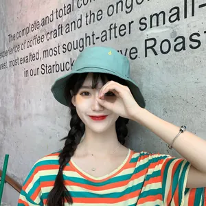 Modelo que luce un elegante sombrero de pescador verde de verano con bordado amarillo de detalle