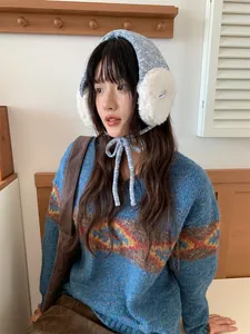 Cache-oreilles tricotés bleus de style coréen portés par un mannequin dans un cadre chaleureux