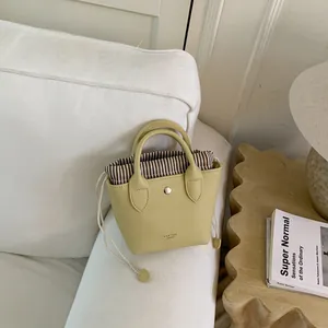 Vue détaillée d'un mini sac seau en cuir grainé jaune sur un canapé blanc