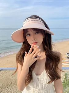 Visière de soleil rose clair à large bord pour femmes dans un cadre de plage d'été