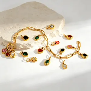 Détail de breloques en acier inoxydable doré avec pierres de zircon colorées sur pierre.
