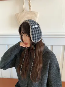 Close-up of model wearing retro checkered plush earmuffs with tie details