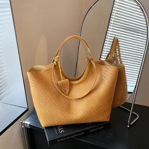 Detail view of a yellow woven tote bag placed on a book next to an arched mirror