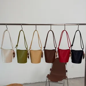 Detailansicht von geflochtenen Eimertaschen in verschiedenen Farben an einem Kleiderständer