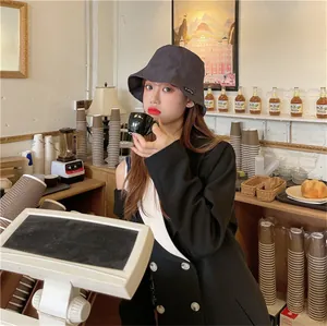 Stylish women's pleated charcoal grey bucket sun hat in a cozy cafe setting.