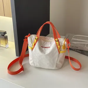 Detail of a white gridded yoga fitness bag with vibrant orange straps and handles