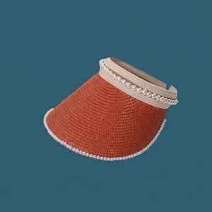 Detail view of an orange woven sun visor with elegant pearl trim embellishments.