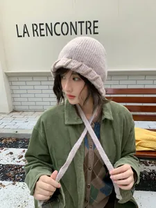 Stilvolle Frau mit einer gemütlichen rosa Strickmütze mit Ohrenklappen im Freien.