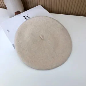 Top view detail of an off-white wool beret hat with a soft felt texture and simple design