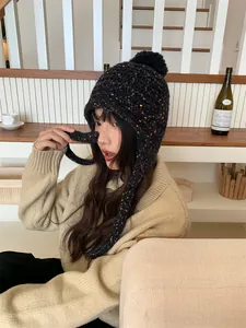 Colorful speckled knit beanie with pom-pom and earflaps for winter warmth.