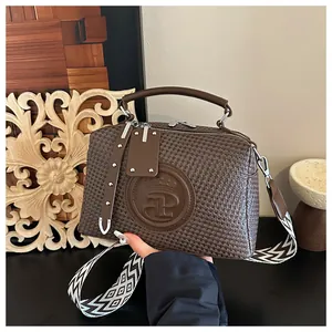 Detailansicht der braunen Handtasche mit Hahnentrittmuster, Kronenlogo und gewebtem Gurt