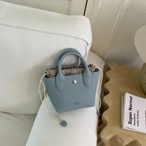 Gros plan d'un mini sac seau bleu clair avec une doublure à cordon de serrage rayée