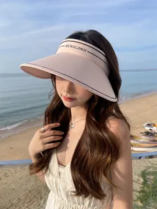 Vue détaillée d'une visière pare-soleil rose à large bord pour femme à la plage