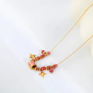 Vue détaillée d'un collier doré élégant avec des perles roses et des étoiles à quatre branches