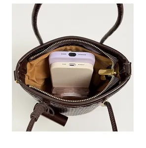 Detail view showing large internal capacity of brown woven bucket bag with phones