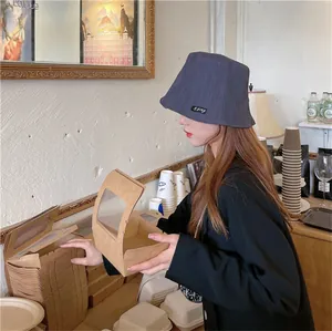 Stylish pleated navy bucket hat for women shown in a cozy bakery cafe lifestyle setting