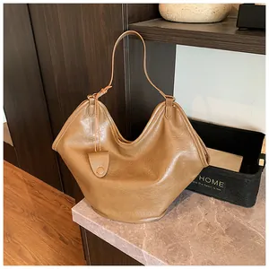 Large brown slouchy leather hobo bag on a marble countertop in a cozy home setting