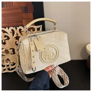 Detailansicht der beigen gewebten Handtasche mit geprägtem Logo und breitem Gurt