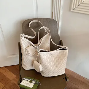 Close-up of woven cream bucket bag with matching mini pouch on chair