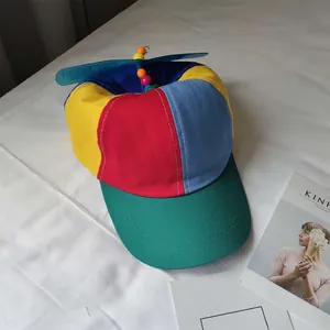 Detail view of a colorful patchwork kids baseball cap with a rotating propeller.