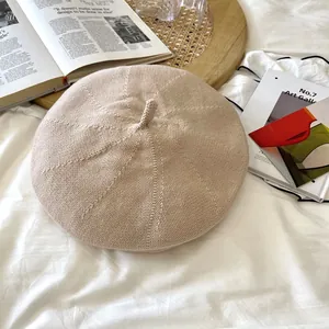 Close-up of beige breathable knit beret with detailed texture in artistic setting
