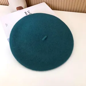 Close-up detail of the teal wool beret showing its soft felt texture and vintage design