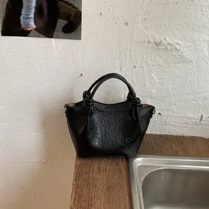 Detailed view of black vintage-style bucket bag featuring unique knotted handle accents