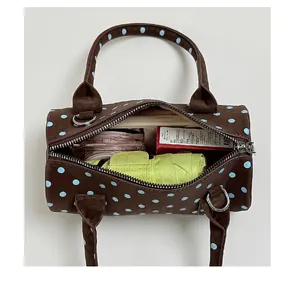 Detailed view showing large internal capacity of brown polka dot cylinder handbag
