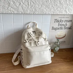 Detailansicht eines cremeweißen Damenrucksacks mit sternförmigen Riemen und Metallnieten.