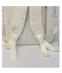 Detail of white floral backpack showing reinforced shoulder straps and adjustment buckles