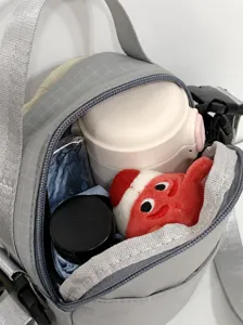 Binnenkant van grijze crossbodytas toont ruimte voor een waterfles en paraplu.